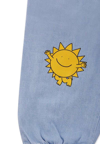 Tessuto di denim azzurro chiaro con un sole giallo in stile cartone animato, con braccia e gambe, sorridente, posizionato al centro del materiale.
