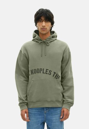 Hoodie vert olive avec cordon de serrage, poche frontale et texte noir en gras sur la poitrine. Tissu doux avec une coupe décontractée.