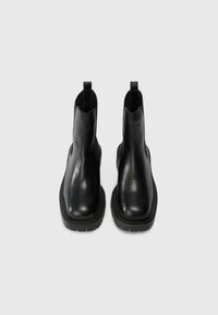 Black leather ankle boots with a smooth finish, rounded toes, and elastic side panels. Features a thick black rubber sole and pull tabs.