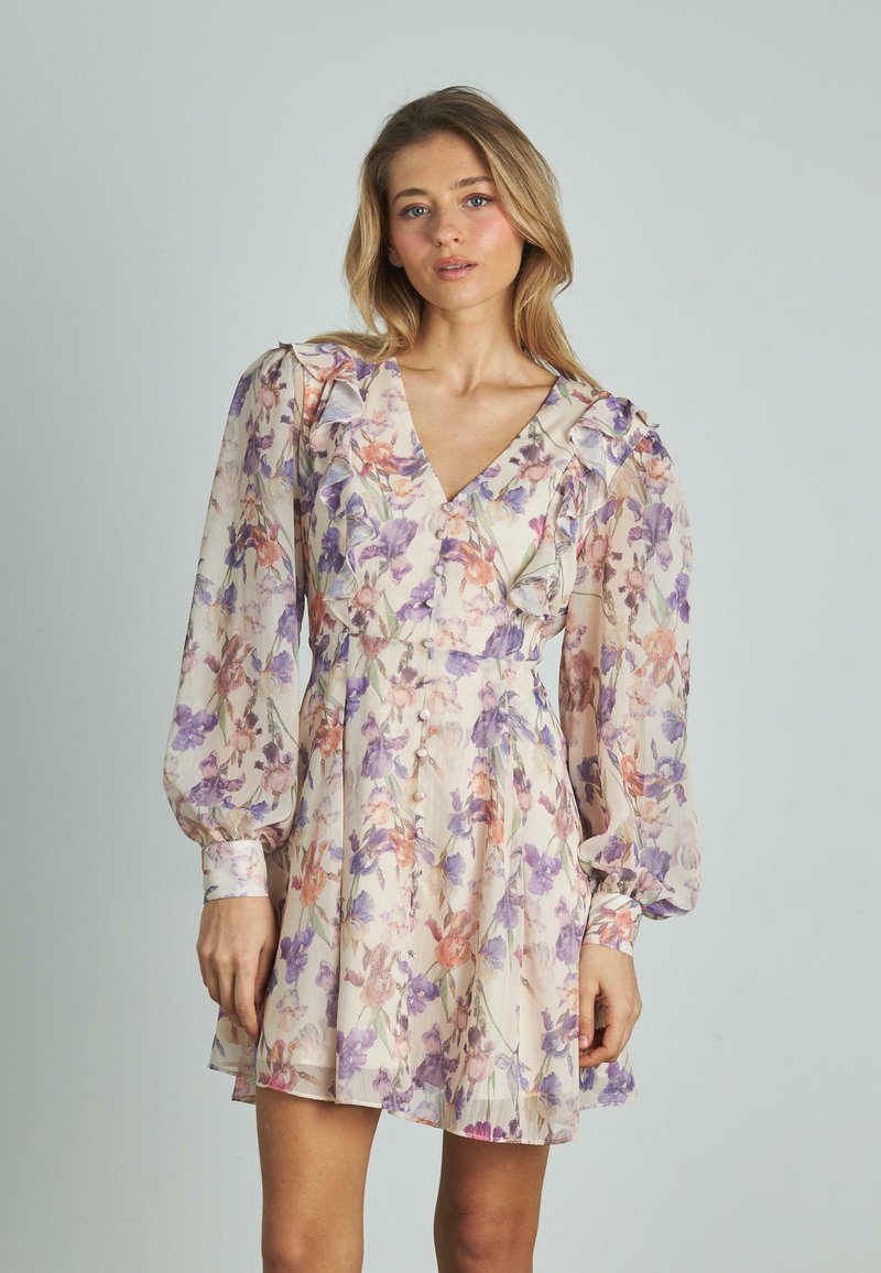 Vestido floral de tela ligera; presenta flores moradas y naranjas, mangas largas abullonadas, escote en V profundo, volantes y detalles de botones en la parte delantera.