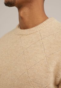 Beige gestrickter Pullover mit einem strukturierten Diamantmuster, Rundhalsausschnitt und gerippten Bündchen. Weiches Material mit einem warmen Finish.