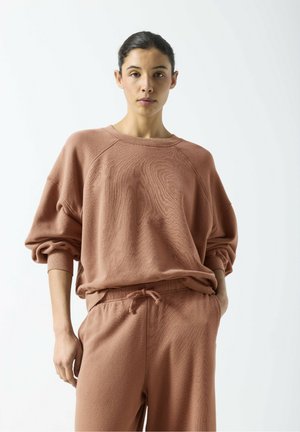 Hellbraunes übergroßes Sweatshirt mit gerippten Bündchen, rundem Ausschnitt und strukturiertem Stoff, kombiniert mit passenden Sweatpants mit Kordelzug.