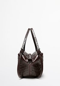 Brun väska i struts läder med dubbla justerbara remmar, dragkedja och rundad form. Texturerad yta med subtila mönsterdetaljer.
