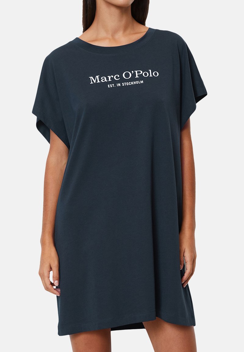 Abito t-shirt corto in cotone morbido di colore blu navy scuro. Presenta un colletto rotondo e la scritta stampata "Marc O'Polo EST. A STOCCOLMA" in bianco.