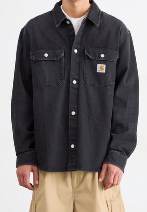 Black denim shirt with two chest pockets, white snap buttons, and a small square logo tag on the left pocket. Long sleeves.