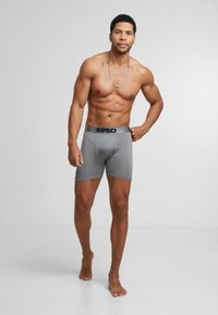Boxers grises avec une taille noire, arborant le logo "PSD". Le tissu semble lisse et la coupe est ajustée.