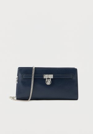 Navy blue leather clutch bag with silver chain strap and silver lock detail on front against white background.