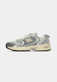 Witte en grijze sport sneaker met gaaspanelen, beige zool en beige "N" logo aan de zijkant.