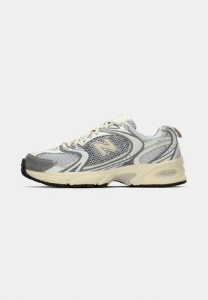 White and gray athletic sneaker with mesh panels, beige sole, and beige "N" logo on the side.