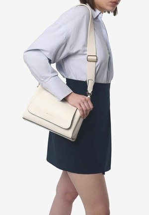White leather shoulder bag with a structured design, featuring a flap closure and adjustable strap, held by a person in a striped shirt.