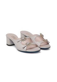 Mule aperte di colore grigio chiaro con due elementi decorativi in cristallo, design con punta aperta e finitura in pelle liscia. Presenta un tacco a blocco basso.