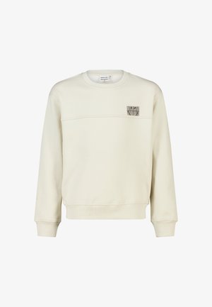 Sweat-shirt crème à manches longues avec col rond et petit écusson carré avec logo sur la partie supérieure gauche de la poitrine.