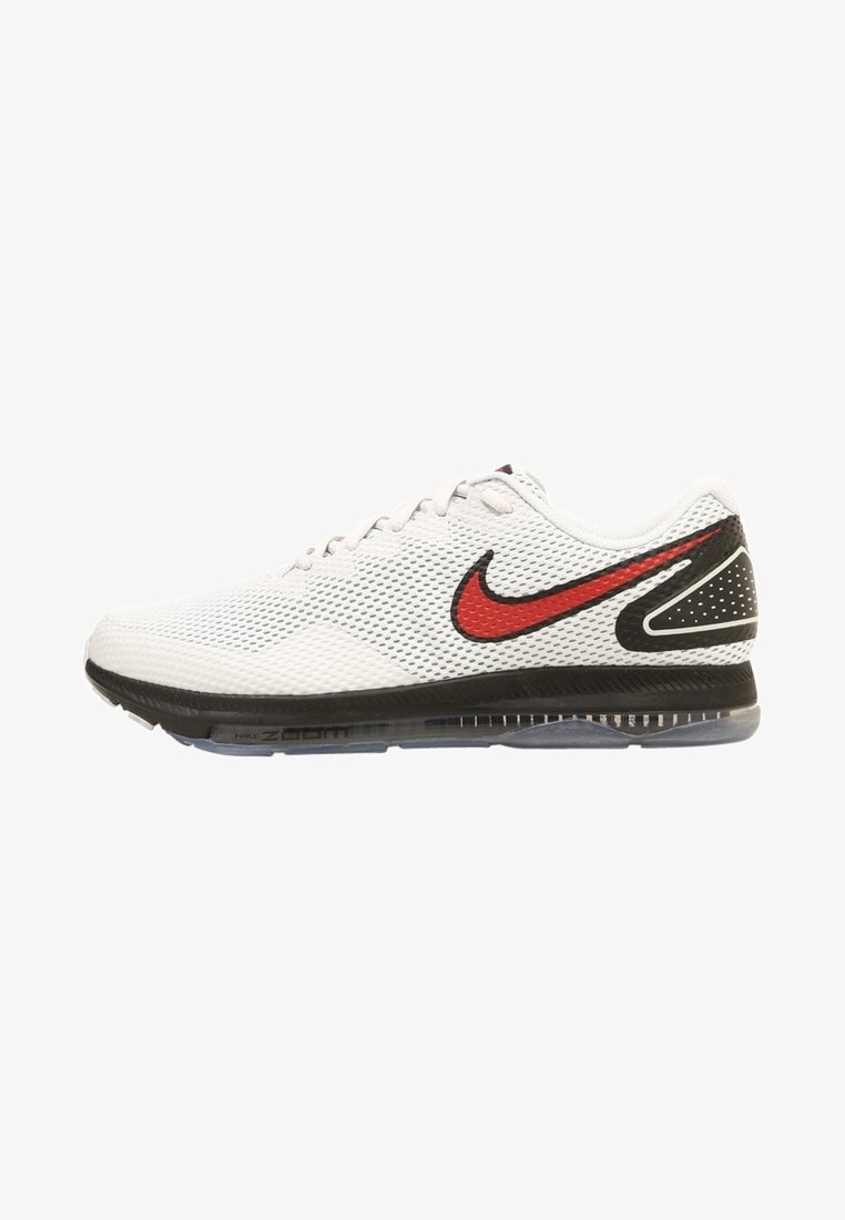 Chaussure de course Nike en mesh blanc avec logo swoosh noir et rouge, semelle noire et amorti transparent, vue de profil sur fond blanc.