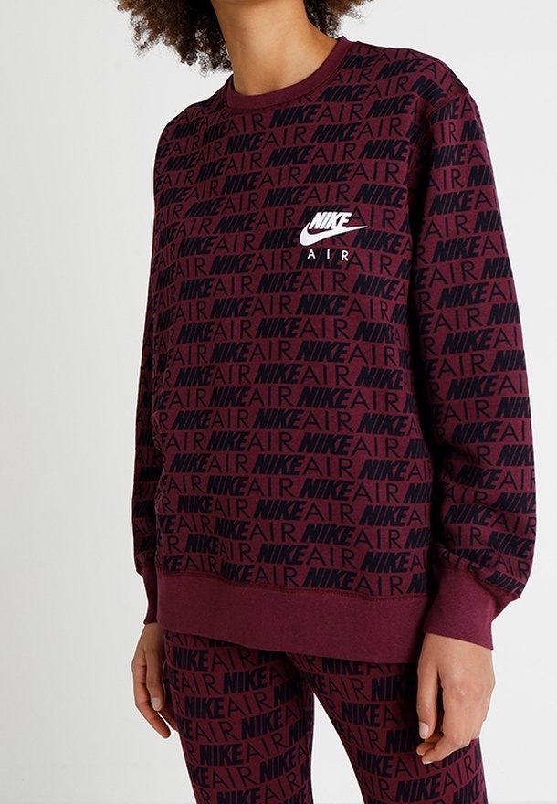 Bordeaux stickad sweatshirt med svart upprepad mönster av "NIKE" och "AIR"; har ribbade ärmslut och nederkant, rund halsringning och liten logotyp på bröstet.