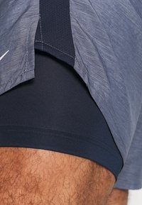 Navy sport short beschikken over een ademend, gestructureerd materiaal met een gelaagd ontwerp. Een goed zittende onderlaag is zichtbaar bij de zoom.