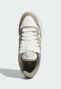 Olivgrön och vit sneaker med en texturerad överdel, perforerat tåparti, vita snören och en märkesdetalj på tungan. Gummisula.