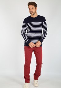 Marineblå og hvide stribede langærmede skjorte sat sammen med røde bukser, fuldendt med hvide sneakers. Enkel design og tætsiddende form.