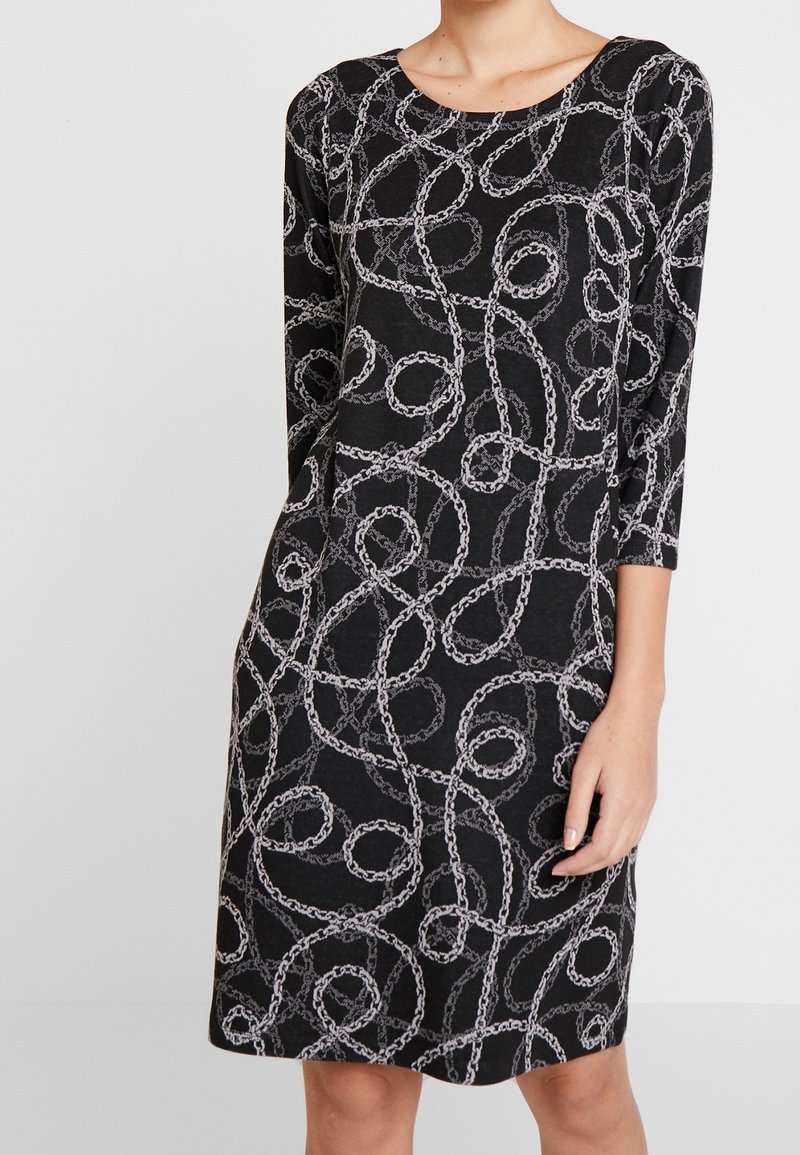 Vestito nero con motivo a catena in argento, con maniche a tre quarti e scollatura tondeggiante, lunghezza fino al ginocchio, in tessuto morbido.