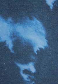 Tessuto di denim con una base blu scuro e un motivo azzurro chiaro simile a delle nuvole, texture liscia e dettagli di tessitura sottili.