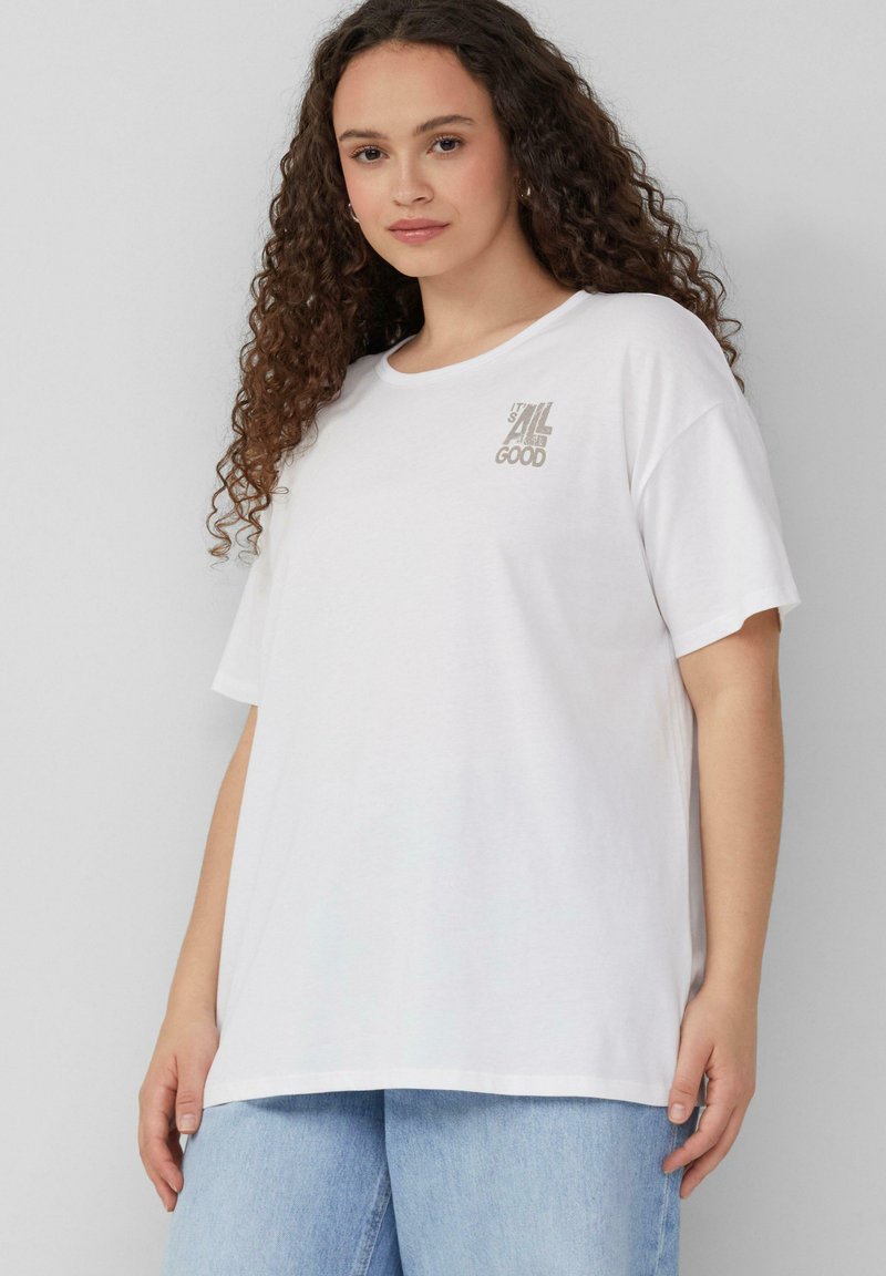 T-shirt en coton blanc avec une coupe décontractée. Il présente des manches courtes et un petit design de texte imprimé en gris au niveau de la poitrine.