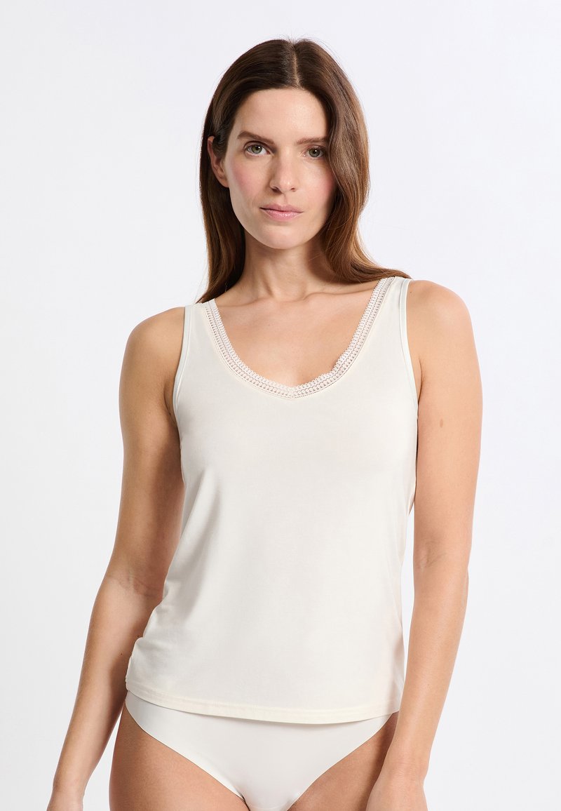 Cream tank top with a V-neck and delicate lace trim around the neckline. Made from soft, smooth fabric with a relaxed fit.