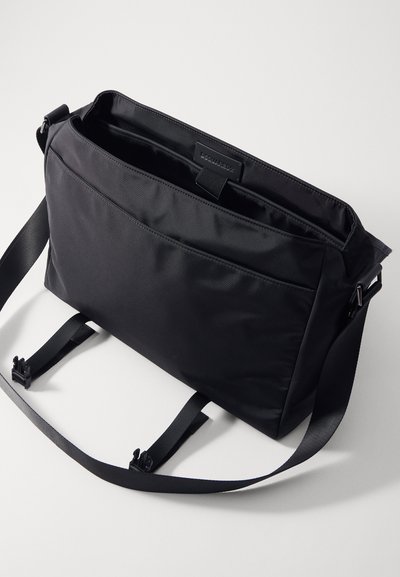 Must musta messenger kott musta nailonist, sujuva tekstuuriga, reguleeritava rihmaga, sise-taskutega ja logotagiga sees. Omab stiilset ja minimalistlikku disaini.