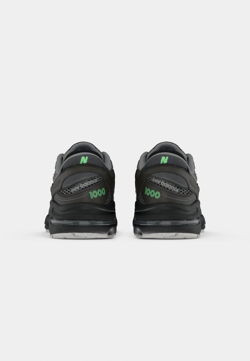 Baskets de sport noires et grises avec un logo "N" vert et le texte "1000". Présente un dessus texturé et une semelle rembourrée avec une finition lisse.