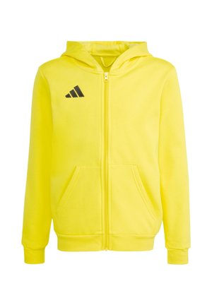 Sudadera amarilla con cremallera completa, bolsillos delanteros, mangas largas, capucha y logo negro de Adidas en el pecho izquierdo.