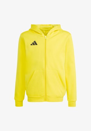 Żółta bluza z kapturem zapinana na cały zamek, z przednimi kieszeniami, długimi rękawami, kapturem i czarnym logo Adidas na lewej stronie klatki piersiowej.
