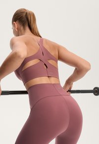 Mavčen športni modrček z izrezom in širokimi naramnicami, v kombinaciji z ujemajočimi se visokimi hlačami z minimalnim šivom in logotipom.