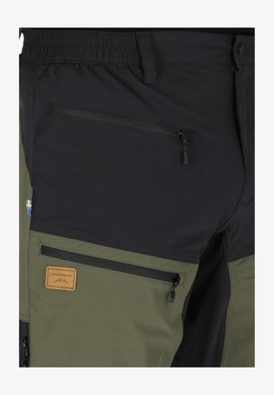 Cargo-Hosen mit schwarzem Oberteil und olivgrünem Unterteil, ausgestattet mit mehreren Reißverschlusstaschen und einem Lederlabel mit dem Markennamen.