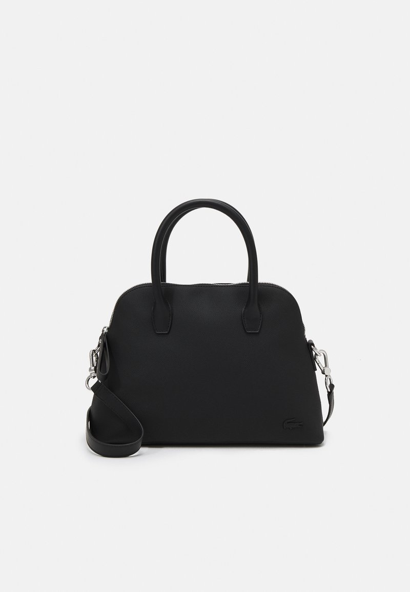 Sac à main noir avec une surface texturée, de forme ovale, deux poignées, une bandoulière réglable et une fermeture éclair. Détail du logo Lacoste sur le côté.