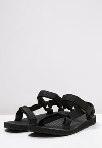 Sandali casual neri con suola in gomma testurizzata, cinturini in nylon regolabili e un design elegante e minimalista.