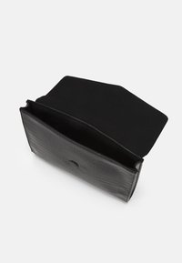 Czarna torba ze skóry z tłoczeniem w kształcie krokodyla, z miękkim materiałowym wnętrzem, prostokątny kształt i zapięcie na klapkę. Otwarty design odsłania wykończenie wnętrza.