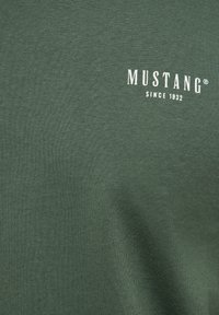 Grøn bomulds T-shirt med en blød tekstur, med "MUSTANG"-logoet og "SINCE 1932" trykt i hvidt på fronten.