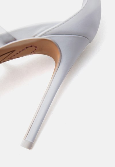Ανοιχτό γκρι γυναικεία γόβα με μυτερή μύτη και λεπτό τακούνι στιλέτο σε λευκό φόντο, γωνιακή όψη που δείχνει το πλάι και τον πάτο.