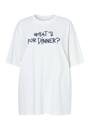 Bílé oversized tričko s černým ručně psaným textem „CO JE K VEČEŘI?“ uprostřed na přední straně.