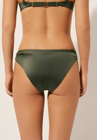 Olivově zelené bikiny s hladkého, lesklého materiálu. Mají řasení na bocích a střední střih na zadní straně.