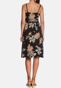Černé květinové šaty s nastavitelnými tenkými ramínky, zúženým pasem a délkou ke kolenům. Mají barevné květinové vzory a měkkou tkaninu.