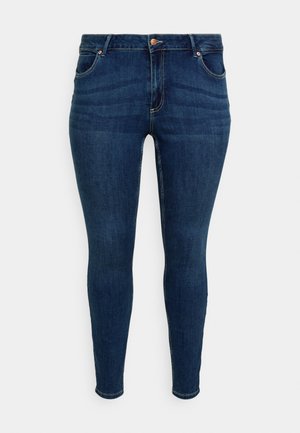 Jeans skinny din denim de culoare albastru închis, cu talie medie, dotate cu cinci buzunare și detalii din metal cu nuanțe de cupru. Textură netedă și formă ajustată.