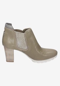 Beige ankelboot med en texturerad yta, elastiska sidopaneler och en lätt upphöjd klack. Har en vit gummisula för bra grepp.