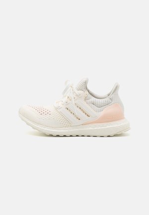 Baskets Adidas Ultra Boost blanches et rose pâle avec tige en maille, fermeture à lacets et semelle rembourrée, vues de côté droit.