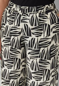 Zwart-witte gestreepte broek met een elastische tailleband, voorzien van een bladvormig ontwerp en een gestructureerde stof.