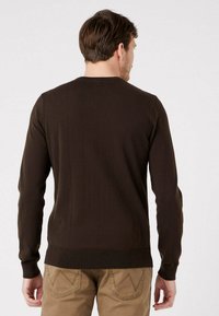 Maglione marrone a maglia con maniche lunghe, polsini e orlo a costine. Collo rotondo semplice, texture liscia con una silhouette aderente.