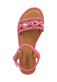 Pink sandals featuring a textured woven strap with sparkling accents, a tan insole, and an adjustable ankle buckle. Flat sole design.