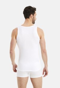 White tank top and shorts made of smooth, stretchy fabric. The tank has a round neck and wide armholes, fitted to the body.