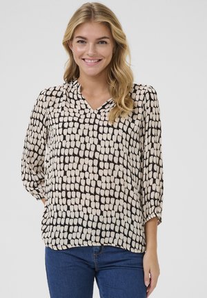 Blouse noire et crème à motif avec un col en V, des manches trois-quarts et une coupe décontractée, présentant une texture de tissu lisse et léger.