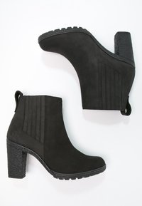Bottines en daim noir avec un talon bloc texturé, présentant des rayures verticales et une bride à l'arrière. Semelle en caoutchouc pour une bonne adhérence.