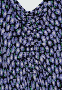 Robe fleurie avec une base noire, présentant un motif floral violet et blanc. Tissu texturé avec des fronces au niveau de l'encolure.