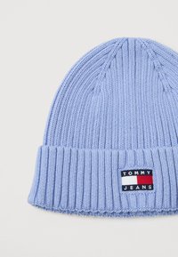 Gaiši zils ribots adījuma cepure ar salocītu maliņu, kurai ir Tommy Jeans loga uzlīme baltā, sarkanā un tumši zilā krāsā.